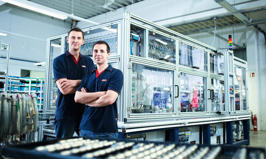 two ABUS factory workers standing in front of production machine