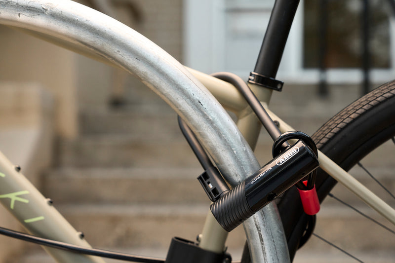 Load image into Gallery viewer, beige bicycle sercured to rack with black ABUS Ultra 410K Mini and cobra cable securing wheels  #size_180mm
