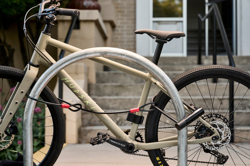 Load image into Gallery viewer, beige bicycle secured to bike race with black ABUS Ultra 410K and cobra cable securing wheels #size_230mm

