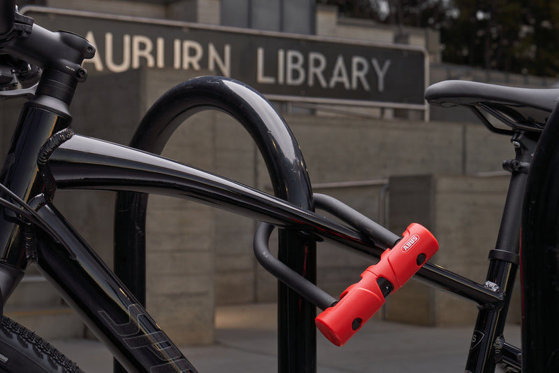 Load image into Gallery viewer, Bicycle locked to a bike rack with &#39;Auburn Library&#39; sign in the background #size_140mm
