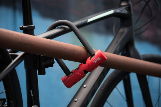 Red U-lock on a bicycle frame against a blurred background