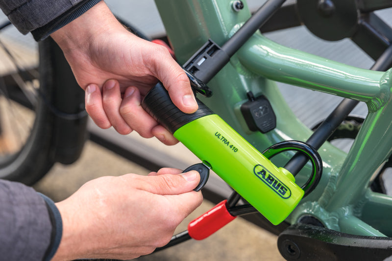 Load image into Gallery viewer, Person unlocking green bike that is secured with green ABUS Ultra 410K #size_230mm
