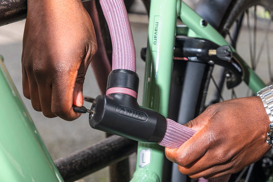 Person securing green bicycle with Rosemauve Goose Lock