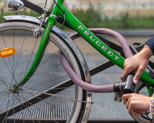 cyclist locking green bicycle to railing with rosemauve ABUS Goose lock.