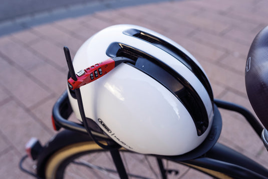 Combiflex TravelGuard in red securing white ABUS Helmet to rear rack of bicycle