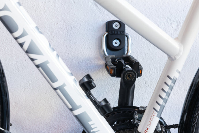 closeup of white bike hanging by pedal on wall 