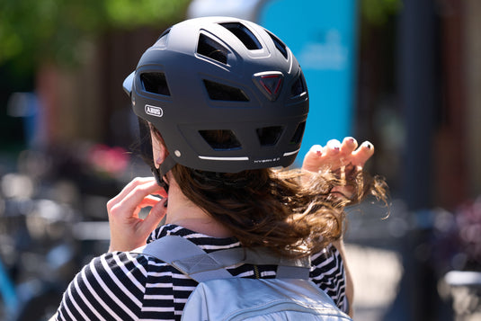 Cyclist adjusting fit of black Hyban 2.0 MIPS helmet