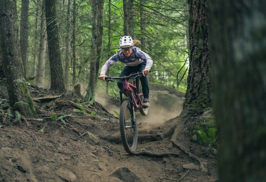 cyclist riding rooty and rough trail in the woods