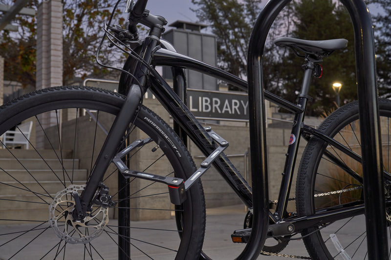 Load image into Gallery viewer, Black bike secured to rack with ABUS Bordo 5700 outside of library #size_80cm
