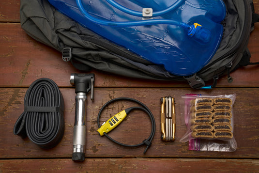 travelguard in yellow next to mini pump, multitool, tube and fig newtons