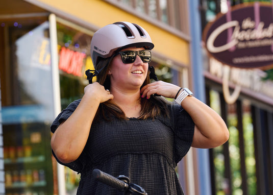 female cyclist adjusting fit of champagne gold ABUS HUD-Y helmet