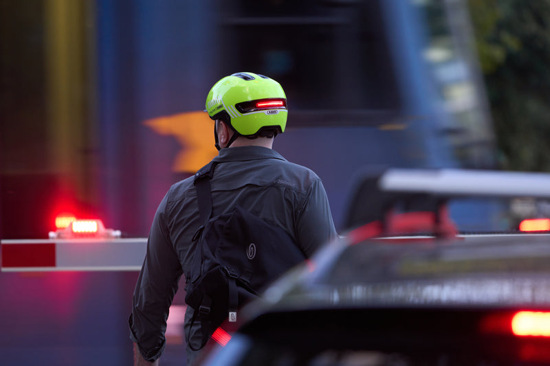 Load image into Gallery viewer, Cyclist near train crossing wearing signal yellow ABUS HUD-Y helemt with light on #color_signal yellow
