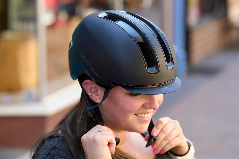 Load image into Gallery viewer, female cyclist adjusting ift of bvelvet black ABUS HUD-Y helmet #color_velvet black

