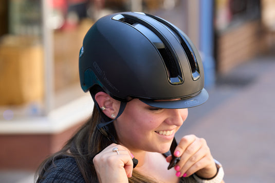 female cyclist adjusting ift of bvelvet black ABUS HUD-Y helmet