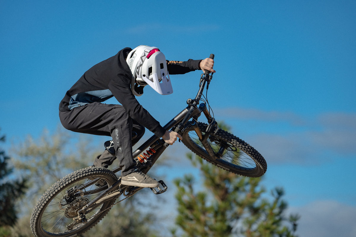 cyclist in mid-air riding mountain bike and wearing white ABUS AirDrop helmet.  