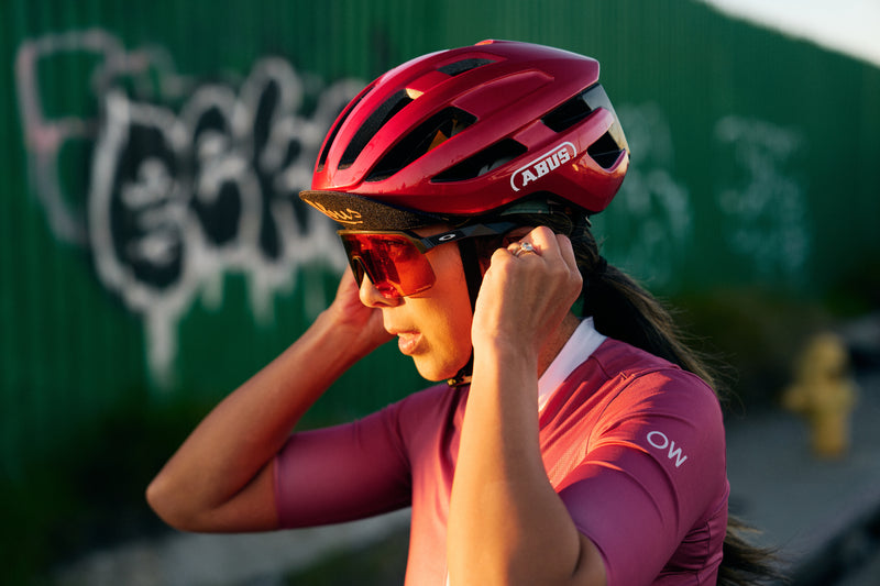 Load image into Gallery viewer, female rider adjusting fit of red ABUS PowerDome #color_performance red

