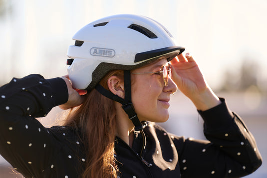 cyclist adjusting fit of white PURL-Y helmet