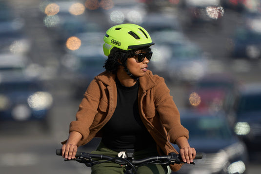 cyclist on busy street wearing yellow PURL-Y helmet